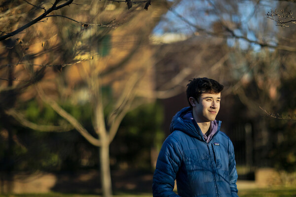 Man in blue jacket on Penn's campus in late afternoon winter light.