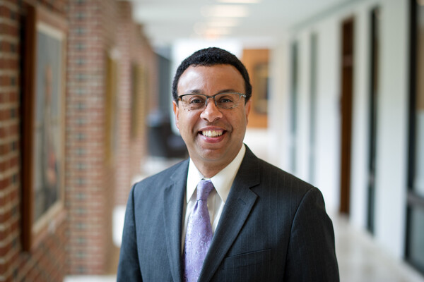 Suited person in hallway lined with portraits