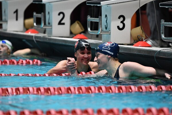 Lia Thomas and a competitor from Harvard grasps hands in the pool after a race at the Ivy Championships.