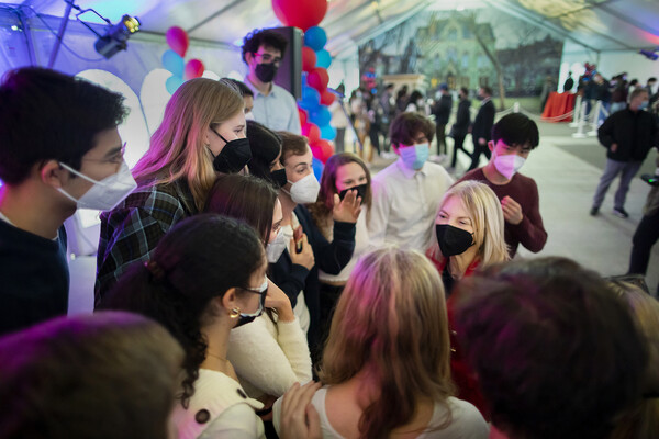 Penn President Amy Gutmann stands among many Penn students in a large tent for a party.