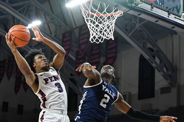 Sophomore guard Jordan Dingle goes up for the shot near the basketball against Yale at the Palestra, maneuvering out of the way of an opponent in midair.