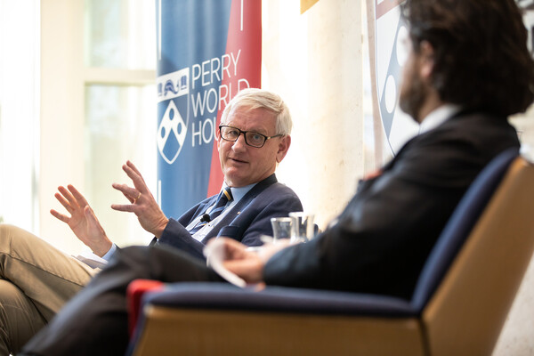 Former Swedish Prime Minister Carl Bildt sits in a chair and gestures while speaking to NYT's Clay Risen