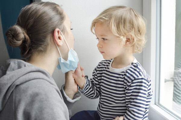 Young child pulling a face mask down off an adult’s nose and mouth.
