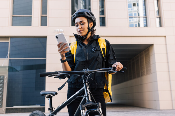 A bike delivery person checks their smartphone.