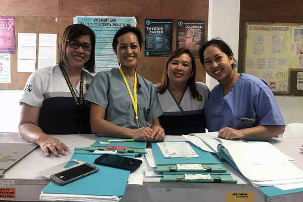Four medical personnel smiling at a desk in a clinic in the Philippines. 