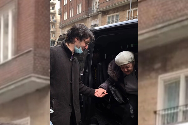 Sam Finkelman helps a Ukrainian woman out of a van onto the street in Hungary