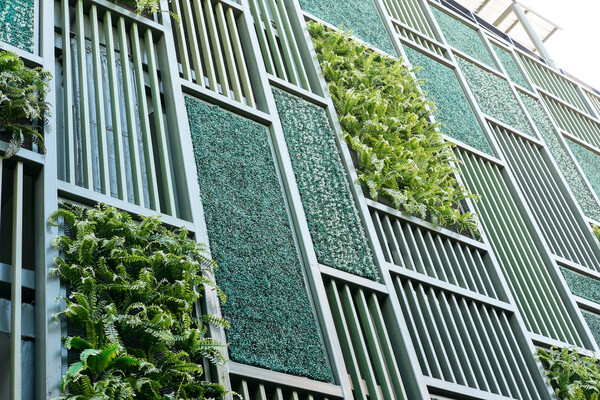 Side of a building. Some of the window spaces are covered with bars. Others are covered with plants and other options for greening the building.