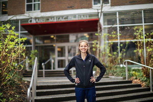 Samantha Roecker standing outside Claire M. Fagin hall with her hands on her hips.