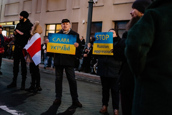 People in the street hold signs that read, in Ukrainian and English, "Stop Russian Aggression."