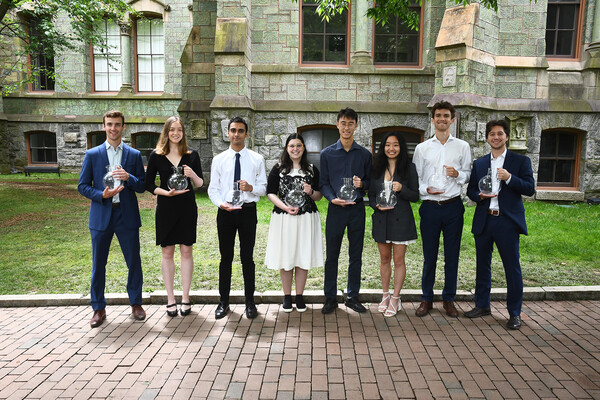 Eight students holding awards in front of College Hall.
