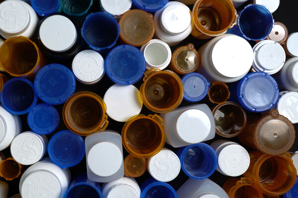 Many empty prescription pill bottles, some with caps removed.
