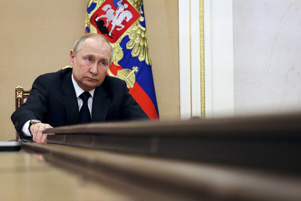 Russian President Vladimir Putin is seen at the end of a long table