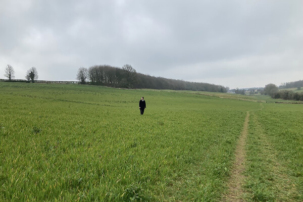 Person standing in a large green field.