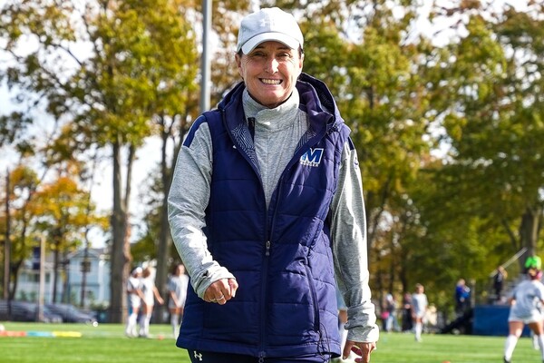 Wearing a Monmouth jacket and gray hat, Krissy Turner walks on the soccer field during her time at Monmouth.