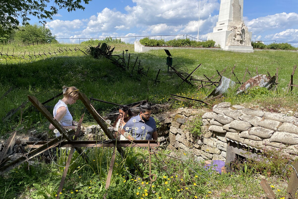 Penn students walk around World War One-era trenches in a French field