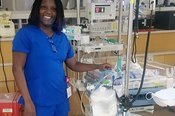 Kimyatta Frazier in scrubs standing in a hospital room.
