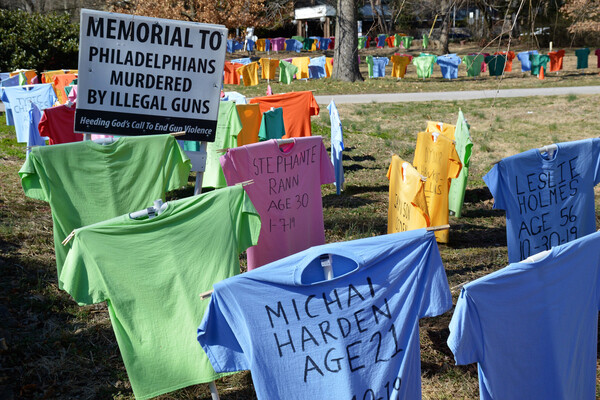 A large grassy area covered in a display of t-shirts erected with names of people killed by gun violence around a sign that reads MEMORIAL TO PHILADELPHIANS MURDERED BY ILLEGAL GUNS.
