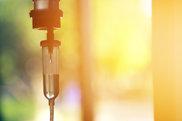 A chemotherapy drip solution hanging by a sunlit window.
