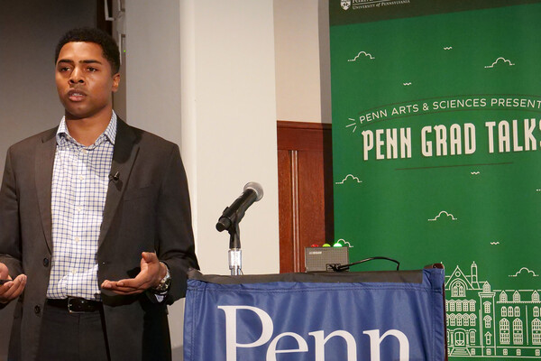 Chad Payne beside podium and microphone with 'Penn Grad Talks' backdrop