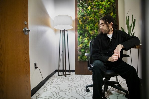 Farhan Jivraj sits at a desk and looks at the topographic rug in the biophilic room