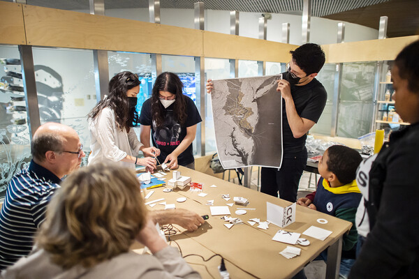 Several people around a table, one holds a satellite map.