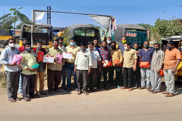 A group of men in India stand in a line holding first aid kits and certificates