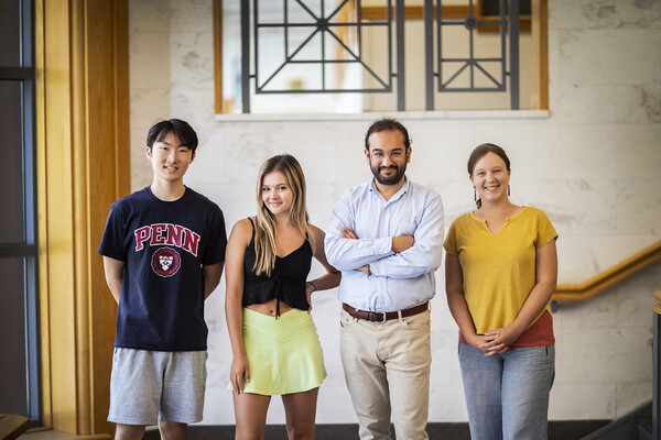 Four people standing at base of stairwell posing for photo