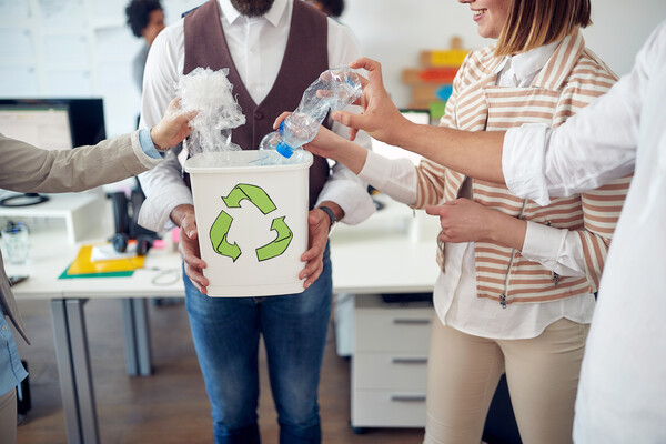 Four office coworkers put their recycling in the bin.