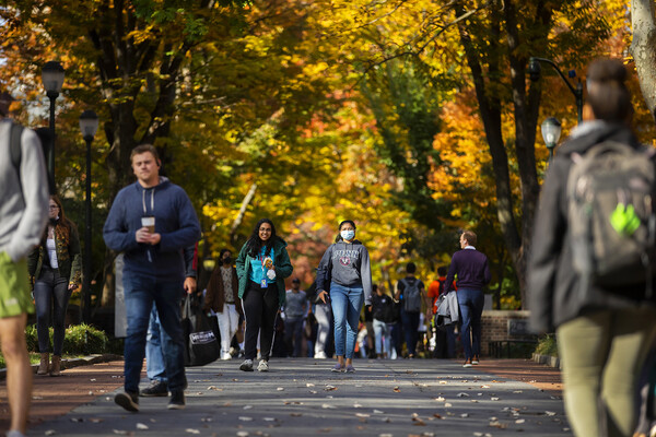 People walking on campus, some with face coverings, some without.