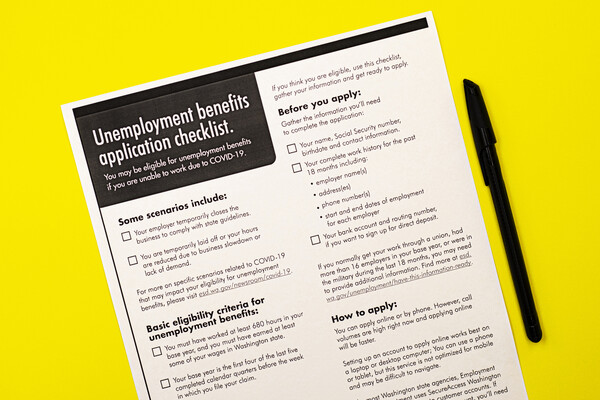 An “Unemployment benefits application checklist” form on a surface next to a pen.