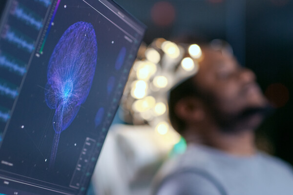 A computer screen displays the brain activity of a man with electrodes on his head.