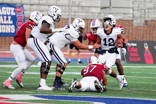 During the Homecoming game versus Yale at Franklin Field, defensive lineman Joey Slackman grabs the Yale quarterback by the ankles and brings him to the ground.