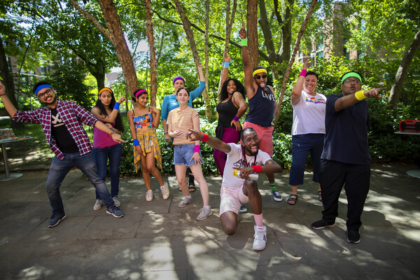 A group of people wearing bright colors strike a pose on the patio of the LGBT Center