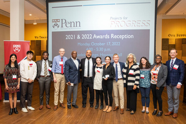 A group of people in front of a PowerPoint that reads "Penn Projects for Progress"