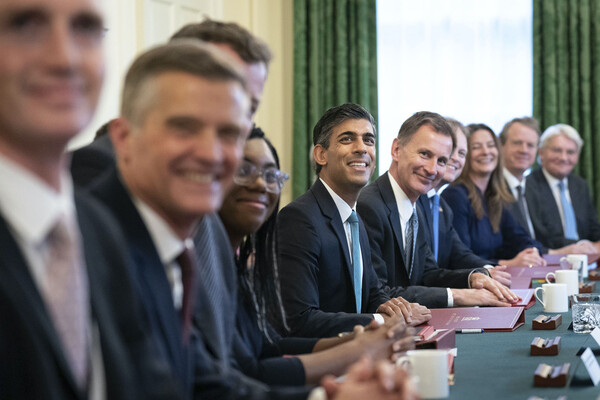 New UK prime minister Rishi Sunak sits at a table with his cabinet at Downing Street in London.
