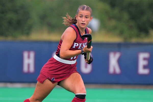 Wearing her red Penn jersey, Meghan Ward runs up the field with her stick in her hands.