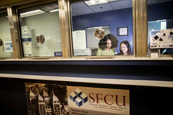 Two student workers behind a bank counter window.