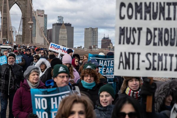 Protesters march across a bridge protesting against hate and antisemitism.