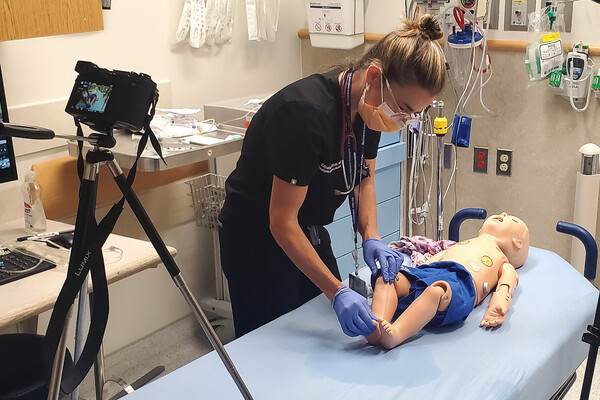 A video camera records Elizabeth Sanseau practicing medical care on a mannequin. (Image courtesy of Kyle Cassidy)