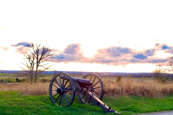 A photograph of a wheeled cannon pointing out at the horizon