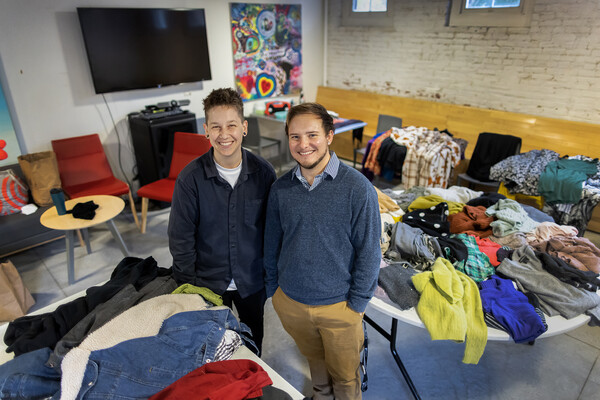 Wes Alvers and Jake Muscato stand amid piles of folded clothing