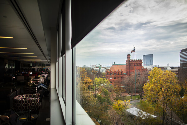 View of Fisher Fine Arts Library and College Green through a large window inside Van Pelt library seating area.