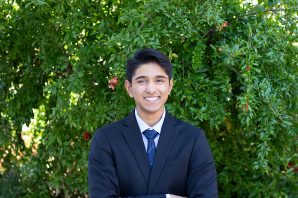 Vikram Balasubramanian standing in front of a leafy hedge wearing a suit and tie
