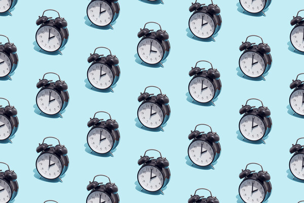 Pattern of black retro alarm clocks show 2 o'clock and one shows 3 o'clock