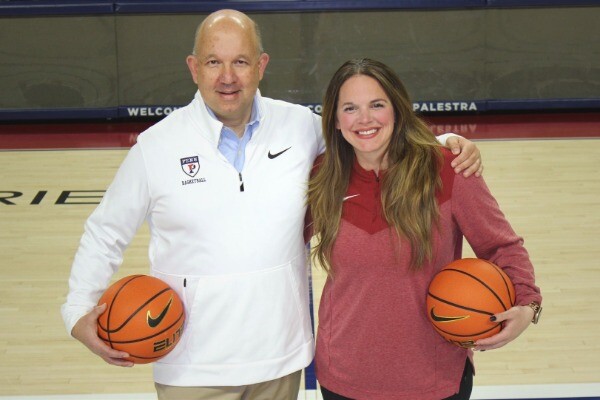 John Di Paolo and Kelly Killion hold basketballs in their arms while standing on the court at the Palestra.