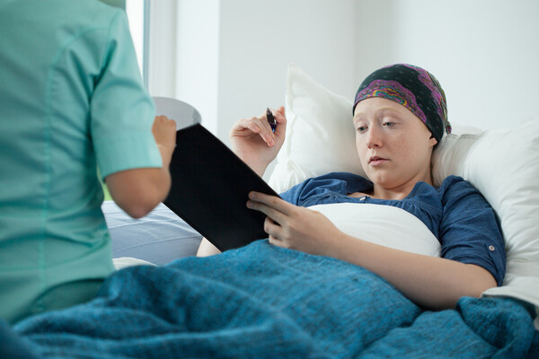  Cancer patient signing a document in a hospital bed.