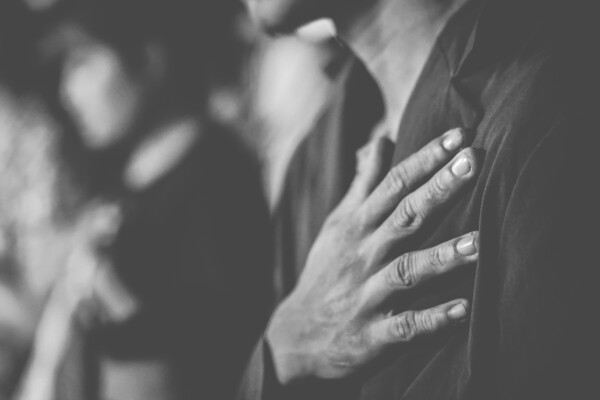 A black-and-white-image of a man with a hand on his heart