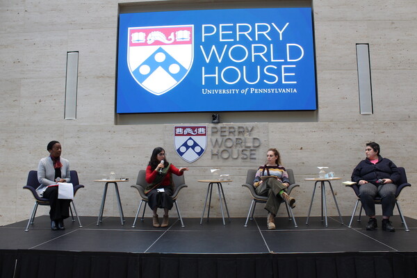 Four people sit on a stage in front of a screen reading "Perry World House University of Pennsylvania" at a talk about Afghan women's rights.
