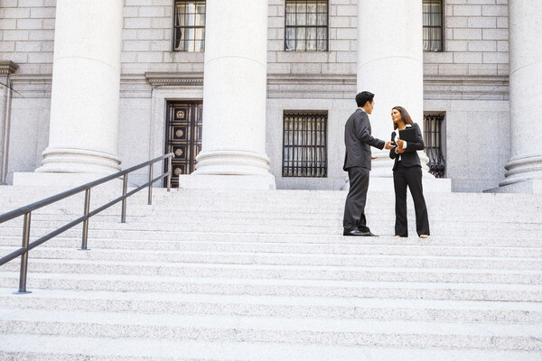 Lawyer and client on the steps outside a courthouse.