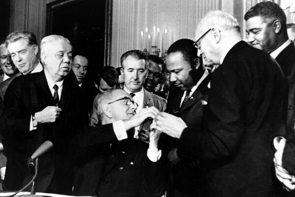 resident Lyndon B. Johnson reaches to shake hands with Dr. Martin Luther King Jr.